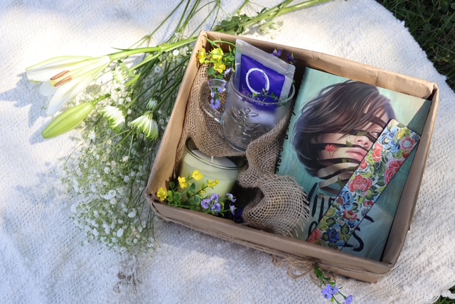 A beautifully arranged book basket with a book, candle, and flowers